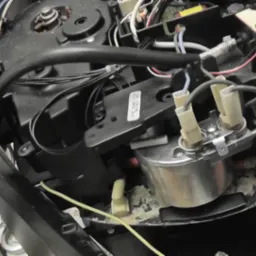 Wnętrze kuchenki mikrofalowej z widocznymi elementami elektrycznymi, przewodami i zabrudzeniami, sugerujące naprawę lub serwis.