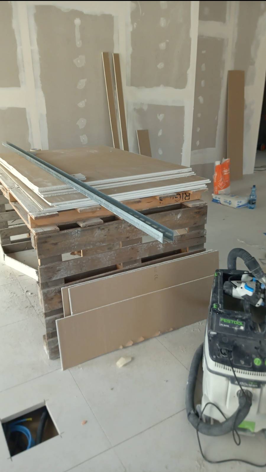 Przygotowane płyty karton gips na palecie z profilami metalowymi, widoczny odkurzacz przemysłowy Festool i instalacja elektryczna w podłodze, Wrocław.