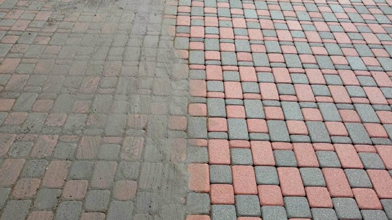 Częściowo umyta kostka brukowa w odcieniach szarości i czerwieni, prezentująca efekt przed i po czyszczeniu. Widoczna wyraźna różnica w kolorze i czystości.