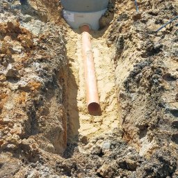 Zbigniew Kańtoch - Montaż betonowego zbiornika z rurą w wykopie w Rudzie Śląskiej, widoczne narzędzia i pracownicy w tle.