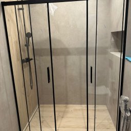 valentyn haliev - Nowoczesna kabina prysznicowa z czarnymi profilami i szklanymi drzwiami przesuwnymi, zamontowana w łazience wykończonej płytkami w odcieniach beżu i szarości, widoczna bateria prysznicowa w kolorze...