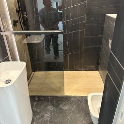 valentyn haliev - Nowoczesna łazienka z czarnymi płytkami imitującymi marmur, kabiną prysznicową typu walk-in z drewnianym brodzikiem, białą umywalką nablatową i toaletą w trakcie prac wykończeniowych, widoczny...