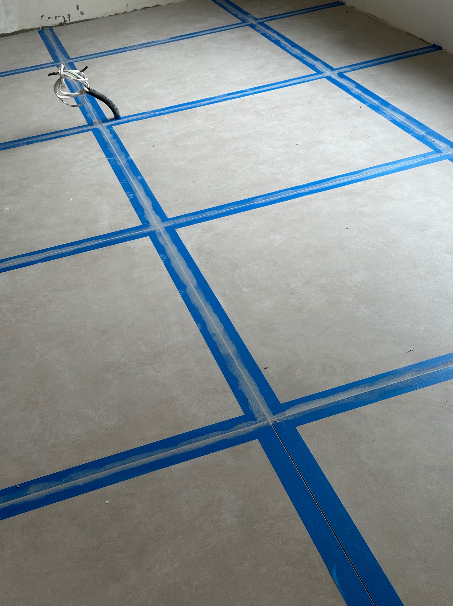 Przygotowanie podłoża pod wylewkę samopoziomującą z użyciem taśmy dylatacyjnej, widoczne wystające przewody elektryczne.