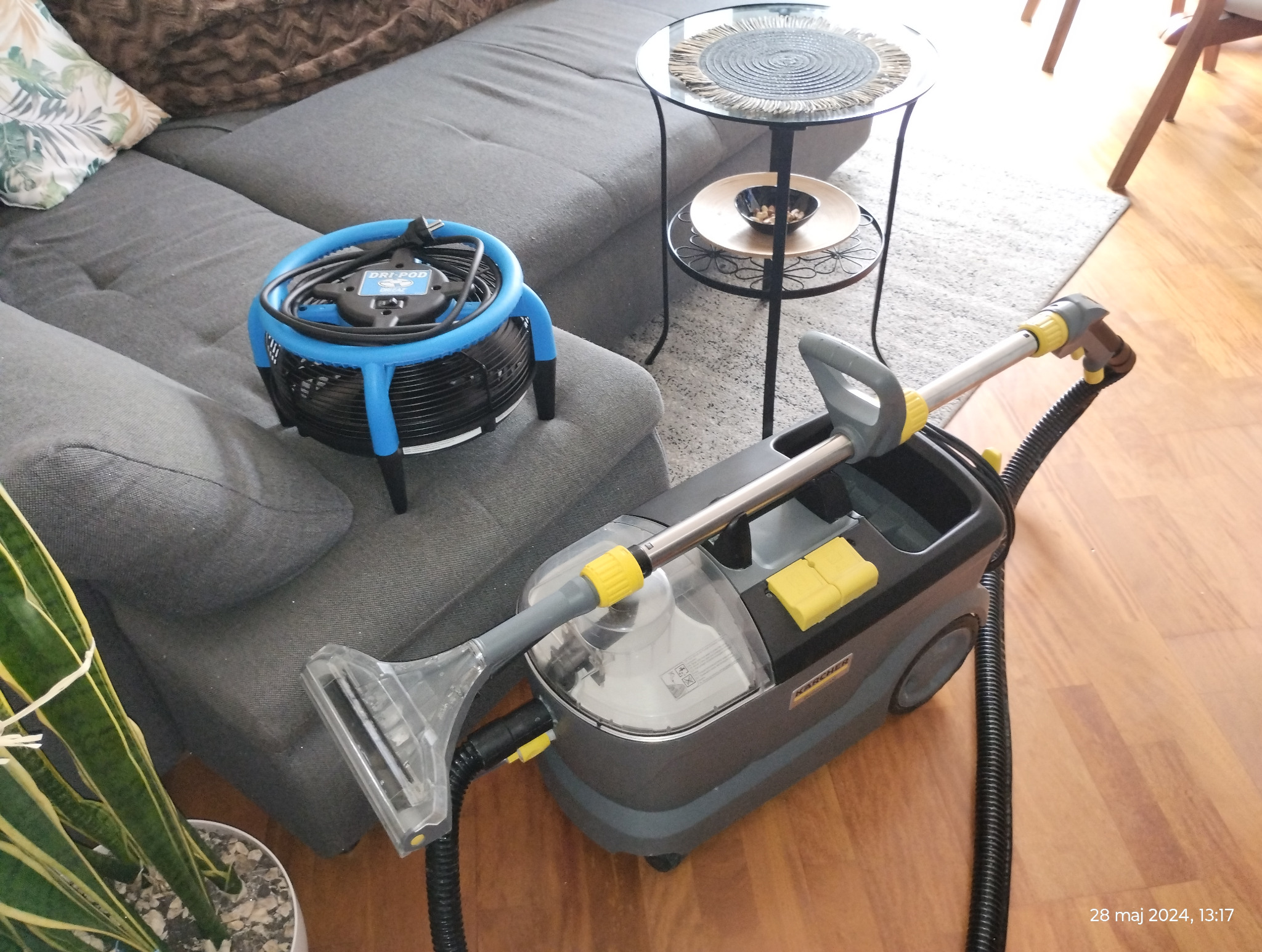 Sprzęt do czyszczenia tapicerki meblowej Karcher i okrągły wentylator do osuszania na tle szarej sofy i stolika kawowego