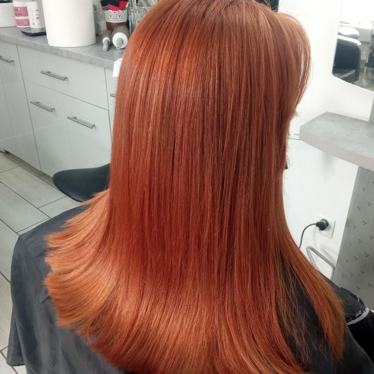 Świeżo ufarbowane, miedziane włosy klientki w salonie, widok z tyłu, z delikatnym podwinięciem końcówek.