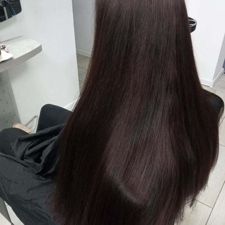 Długie, proste, ciemnobrązowe włosy po koloryzacji, widoczne z tyłu, w salonie fryzjerskim, z delikatnym połyskiem.