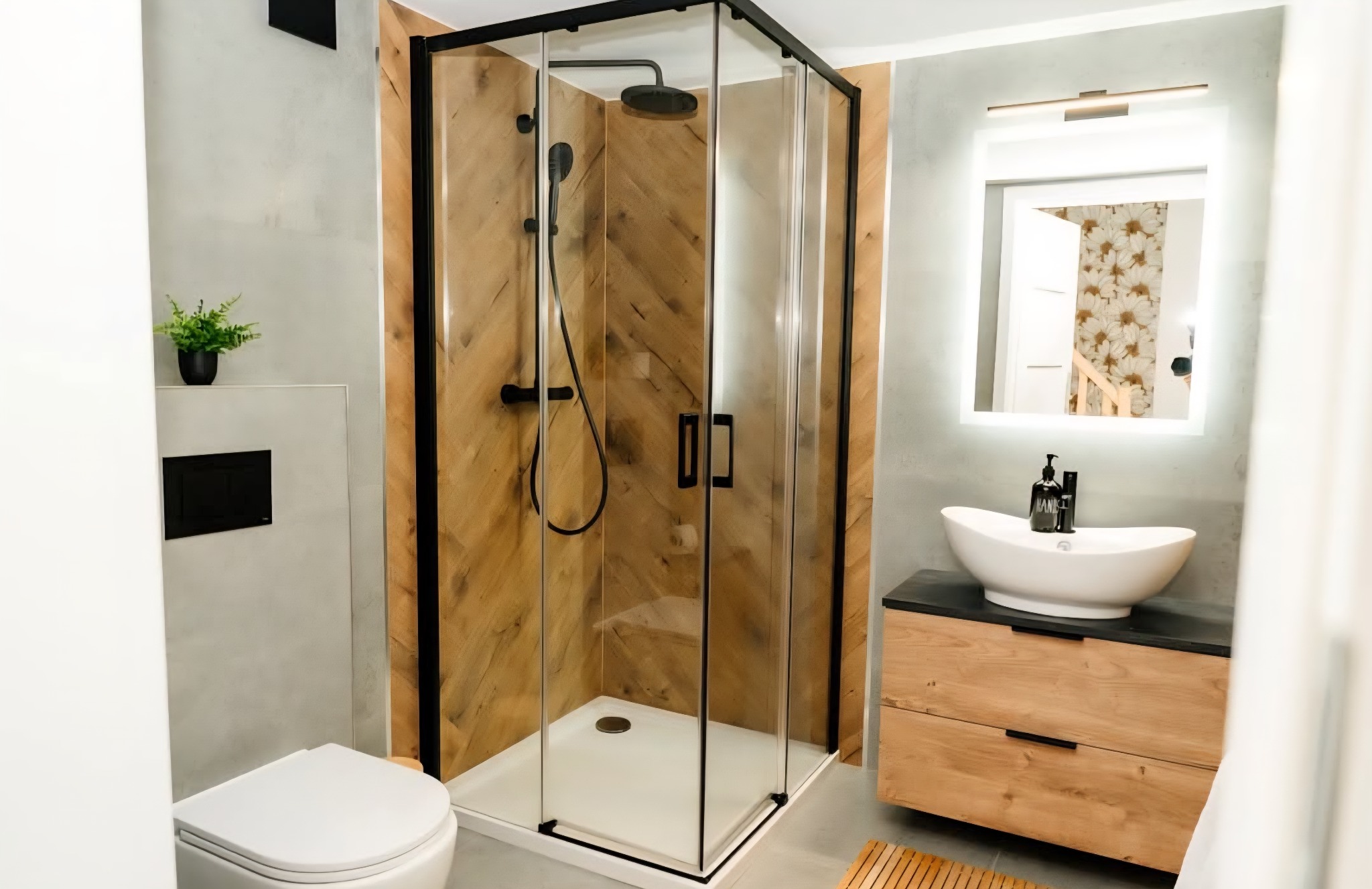 Nowoczesna łazienka z kabiną prysznicową typu walk-in, umywalką nablatową i drewnianymi akcentami. Minimalistyczny design z rośliną doniczkową.