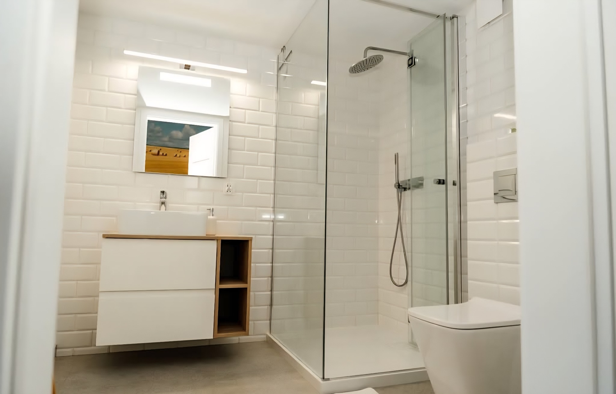 Nowoczesna łazienka z białymi, cegiełkowymi płytkami, kabiną prysznicową ze szklanymi drzwiami i szafką pod umywalką z drewnianymi półkami. Minimalistyczny design.