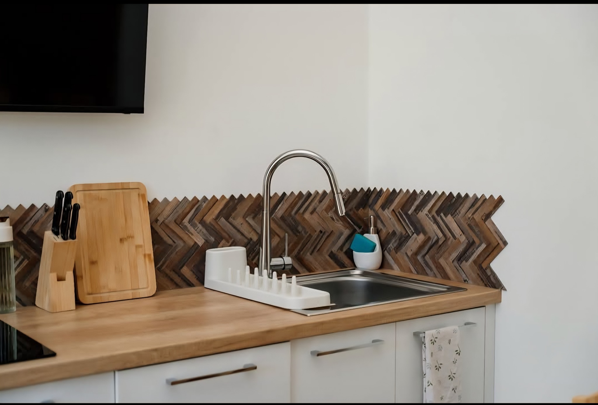 Wykończona kuchnia z drewnianą mozaiką nad blatem i zlewozmywakiem w Ostrowie Lubelskim. Nowoczesny design z elementami naturalnego drewna.