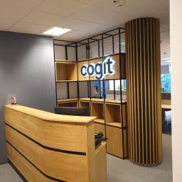 Best Project Sebastian Łobacz - Recepcja biurowa z drewnianą ladą o falistym froncie, regałem z podświetlanym logo firmy 'cogit' i kolumną z pionowych listew w kolorze drewna i czerni.