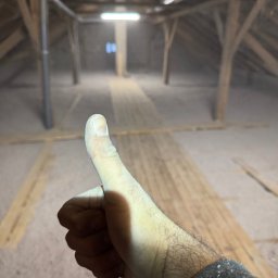 X-Term - Kciuk w górę, prawdopodobnie po zakończeniu prac na nieocieplonym poddaszu ze starą drewnianą konstrukcją i widocznymi deskami podłogowymi.