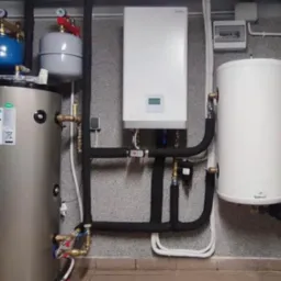 Kotłownia z piecem gazowym, zasobnikiem ciepłej wody i naczyniami przeponowymi, rury w izolacji termicznej prowadzone wzdłuż ściany o strukturze baranka.