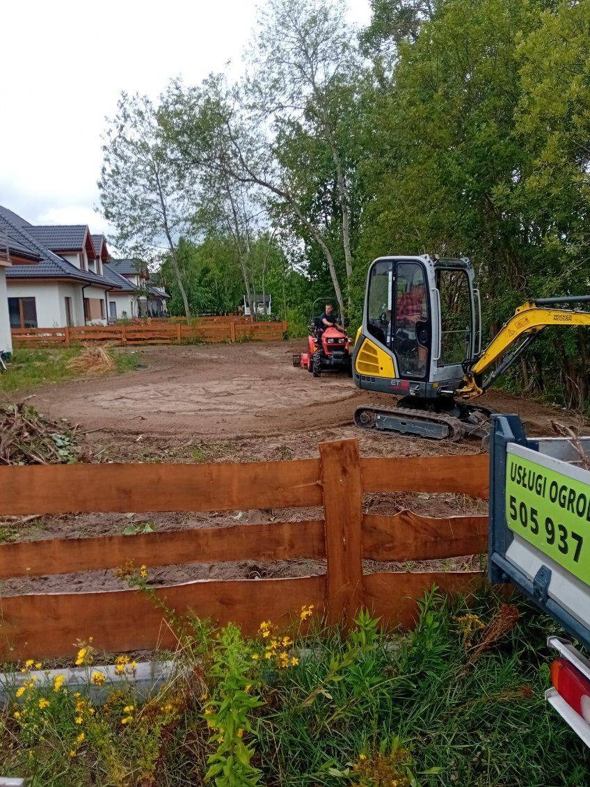 Teren przygotowywany pod przyszły ogród: mini koparka Wacker Neuson i mały traktor wyrównują ziemię za drewnianym ogrodzeniem, w tle domy jednorodzinne i drzewa.