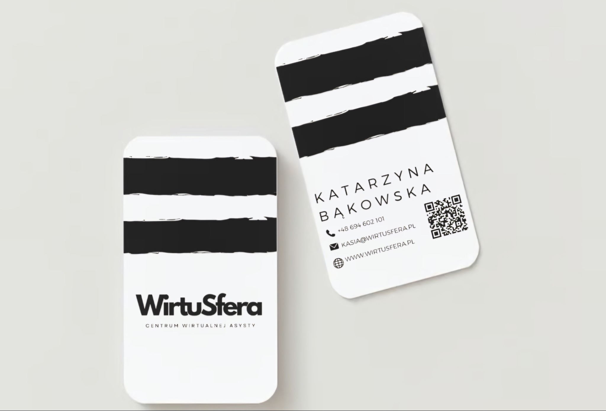 Dwie wizytówki z zaokrąglonymi rogami, jedna z logo 'WirtuSfera Centrum Wirtualnej Asysty' i czarnymi pasami, druga z danymi kontaktowymi Katarzyny Bąkowskiej i kodem QR.