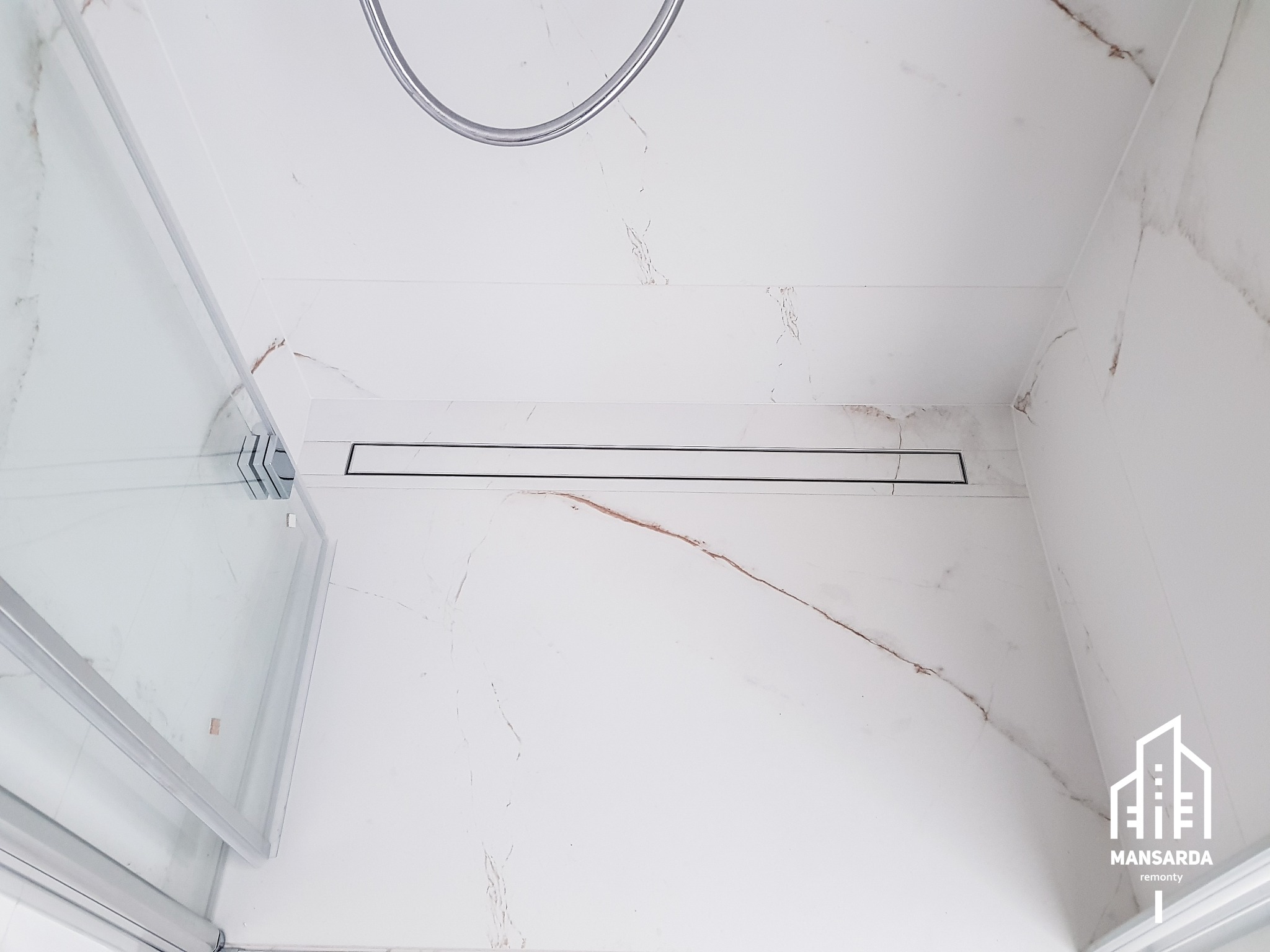 Kabina prysznicowa z odpływem liniowym i białymi płytkami imitującymi marmur w Bielsko-Białej, widok z dołu.