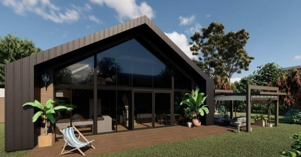 Wizualizacja domu jednorodzinnego z czarną elewacją, dużymi przeszkleniami i drewnianym tarasem, na którym stoi rozłożone krzesło plażowe w paski oraz rośliny w donicach, w tle zielony trawnik...