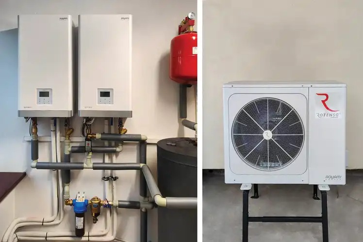 Dwa białe, wiszące moduły grzewcze Aquami Rotenso z podłączeniami hydraulicznymi, obok zbiornik akumulacyjny i czerwony zbiornik wyrównawczy, a po prawej zewnętrzny moduł Rotenso Aquami...