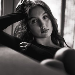 Tomasz Markieiwicz - Portret młodej kobiety w czerni, opierającej głowę na ręce, z melancholijnym spojrzeniem w obiektyw, w czarno-białej tonacji.