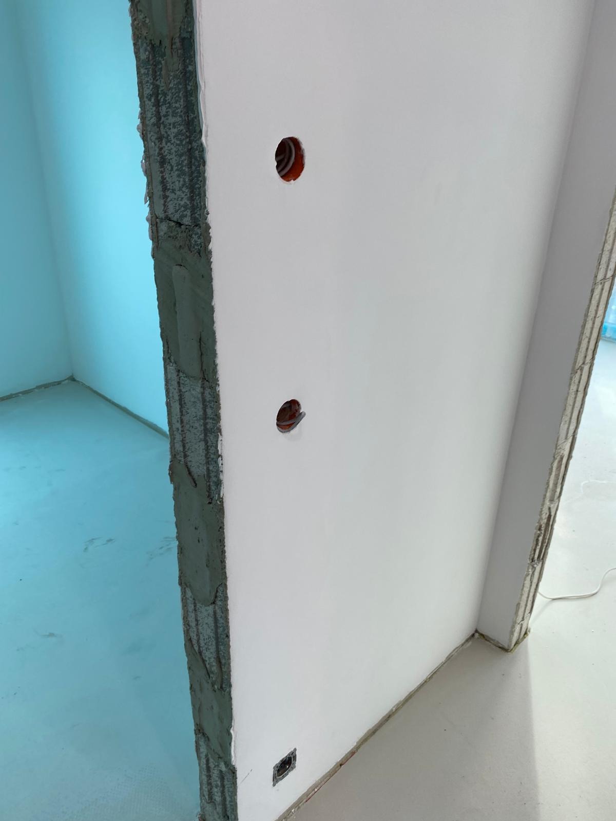 Przygotowanie do montażu gniazdek elektrycznych we Wrocławiu: wywiercone otwory w ścianie, widoczne przewody, surowy stan wykończenia wnętrza.