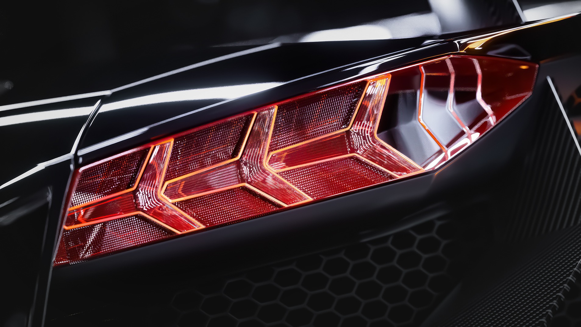 Detaliczne ujęcie tylnej lampy w kształcie litery Y, czerwonej i podświetlonej, czarnego sportowego samochodu z elementami karbonu i siatkową strukturą grilla.