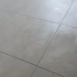 Świeżo położone, jasnoszare płytki podłogowe z ciemnoszarą fugą, widoczne ślady po pracach wykończeniowych.