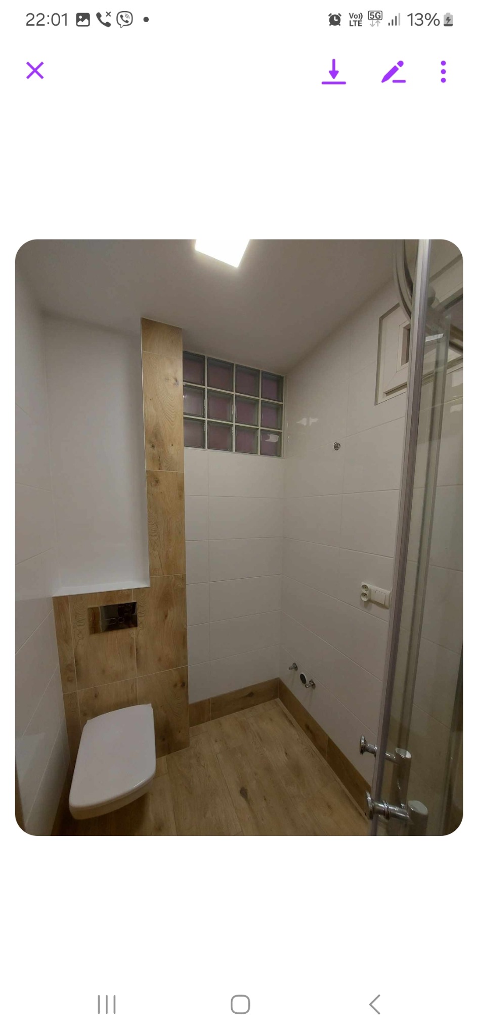 Nowoczesna łazienka po remoncie z kabiną prysznicową, podwieszaną toaletą, wykończeniem w bieli i drewnie oraz oknem z luksferów.