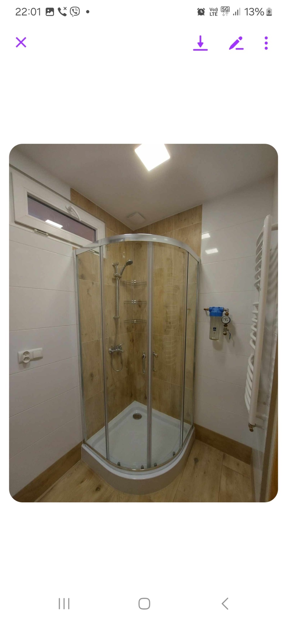 Wykończona łazienka w Bytomiu z kabiną prysznicową z zaokrąglonymi szybami, beżowymi płytkami imitującymi drewno, białymi płytkami na ścianach i drewnianą podłogą, widoczny filtr wody.