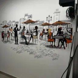 Ilustracja na ścianie przedstawiająca scenę kawiarnianą z sylwetkami ludzi siedzących przy stolikach pod parasolami na tle zarysów budynków miejskich.