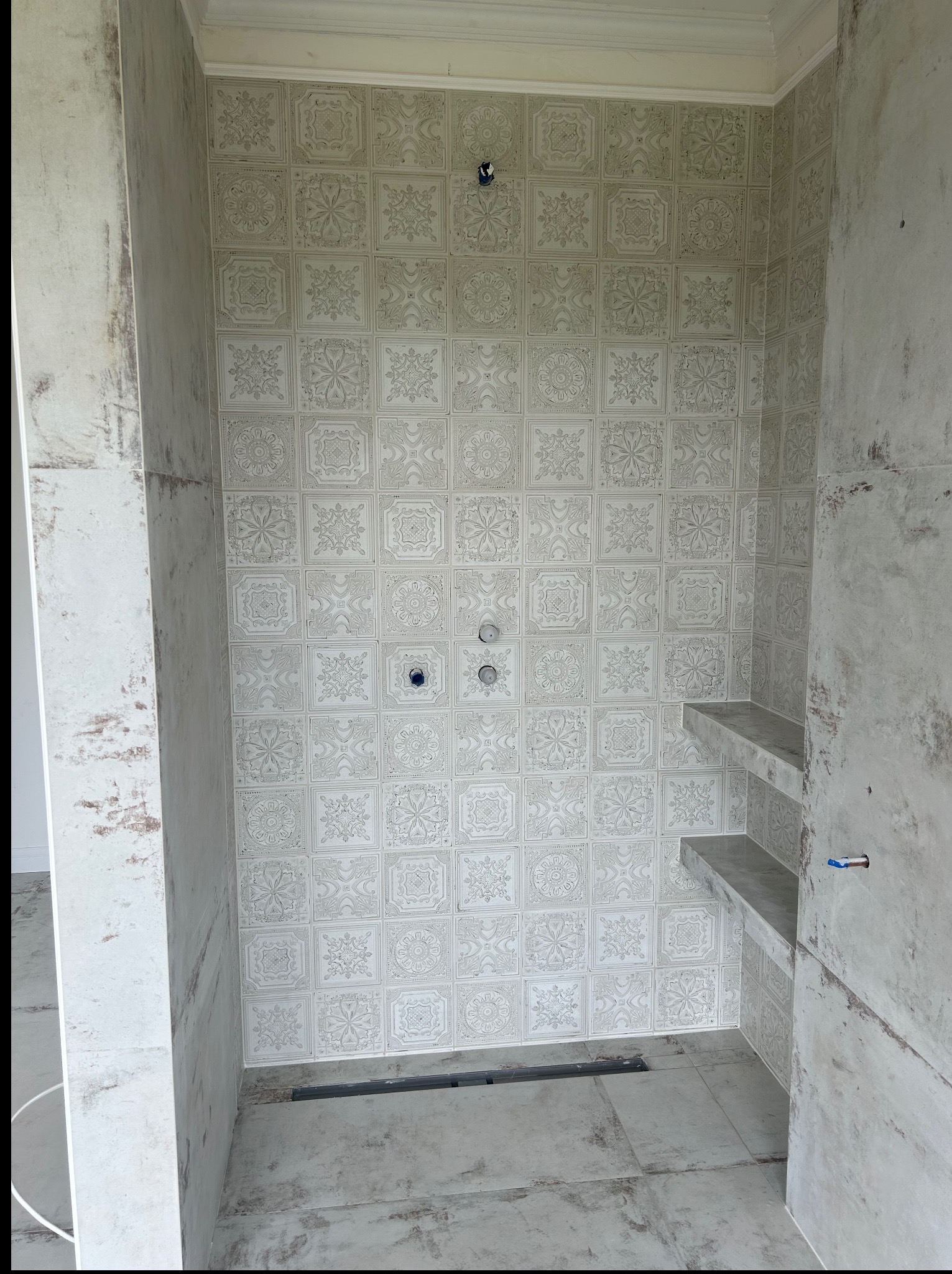 Wykończona kabina prysznicowa w Grudnej Dolnej z dekoracyjnymi płytkami ściennymi i półkami, gotowa do montażu armatury. Minimalistyczny design.