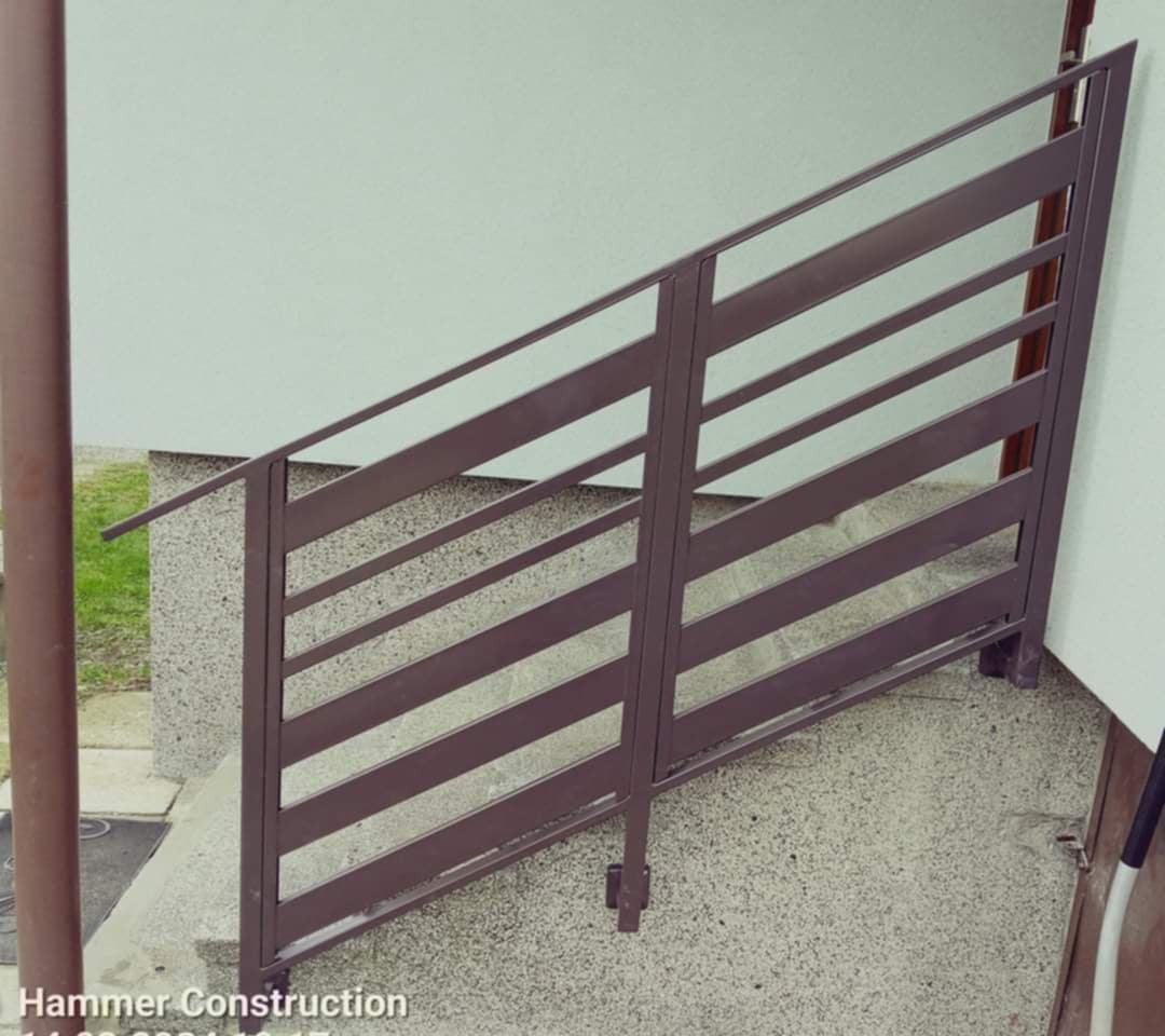 Metalowa balustrada schodowa z poziomymi szczeblami, pomalowana na brązowo, zamontowana przy schodach zewnętrznych, widok z góry.