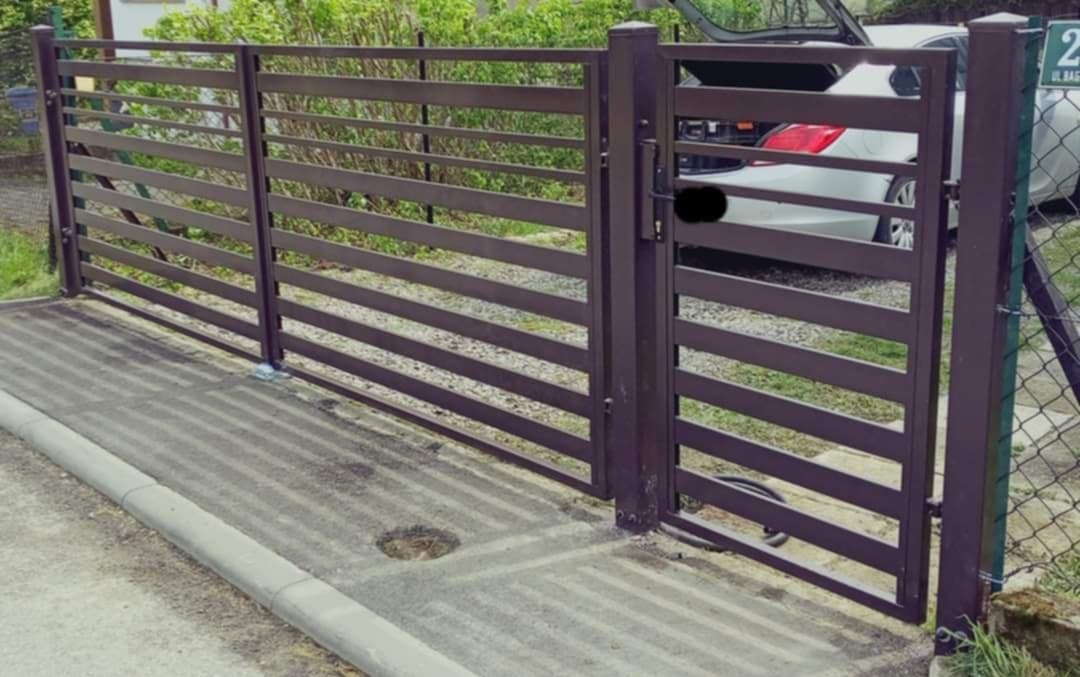 Nowoczesna brama wjazdowa z metalowymi, poziomymi panelami w kolorze ciemnego brązu, z widocznym samochodem z otwartym bagażnikiem w tle.