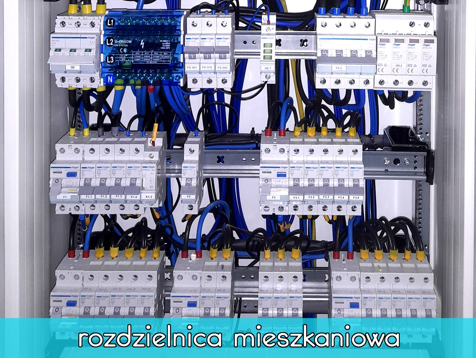 Rozdzielnica elektryczna z licznymi bezpiecznikami i przewodami w kolorach niebieskim, czarnym i żółtym, zamontowana w metalowej obudowie, widok z bliska.