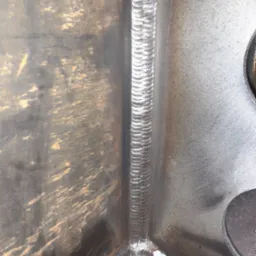 Wewnętrzny narożnik spawanej konstrukcji stalowej, widoczny ślad po spawie i niedoskonałości obróbki powierzchni.