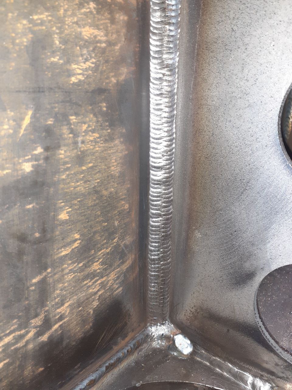 Wewnętrzny narożnik spawanej konstrukcji stalowej, widoczny ślad po spawie i niedoskonałości obróbki powierzchni.