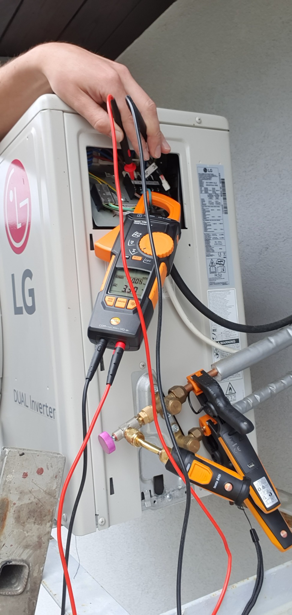 Serwisant w Rokicinach podhalańskich diagnozuje zewnętrzną jednostkę klimatyzacji LG Dual Inverter za pomocą multimetru cęgowego i termometru elektronicznego Testo 549i, sprawdzając parametry pracy...