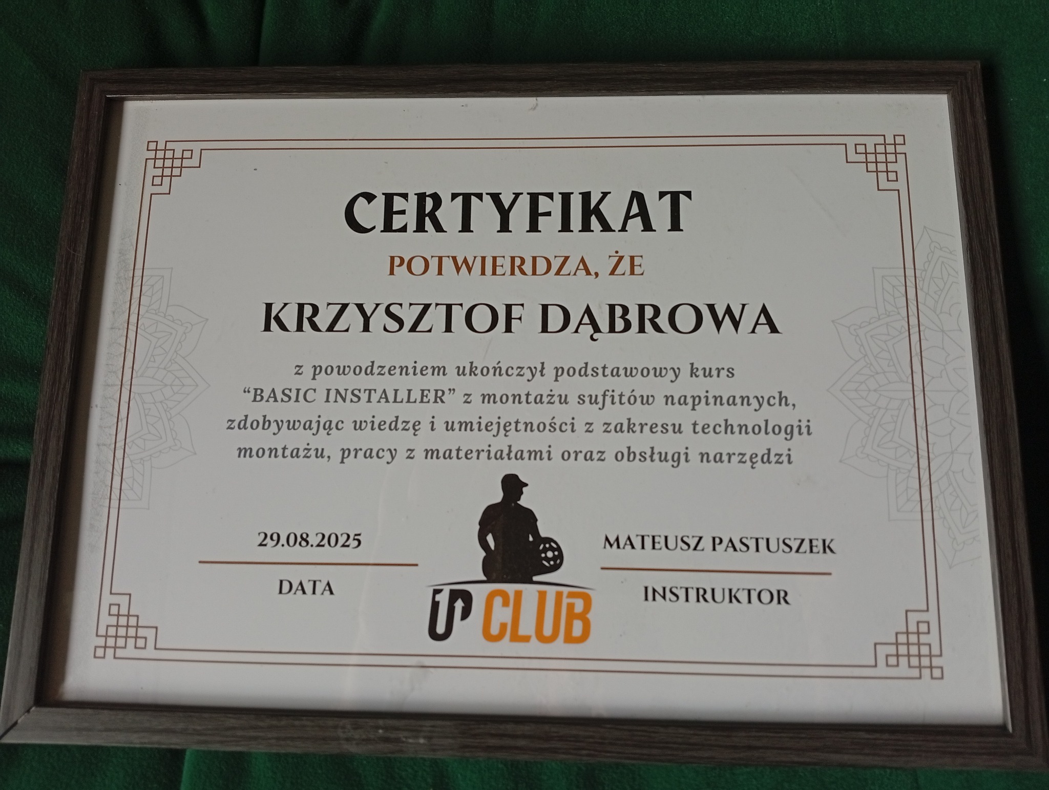 Oprawiony certyfikat ukończenia kursu 'BASIC INSTALLER' z montażu sufitów napinanych dla Krzysztofa Dąbrowy, z datą 29.08.2025, podpisany przez instruktora Mateusza Pastuszka.