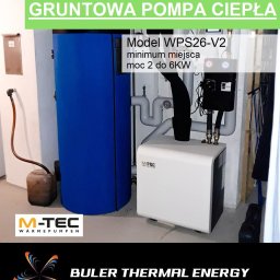 BULER THERMAL ENERGY Piotr Buler - Kompaktowa gruntowa pompa ciepła M-TEC WPS26-V2 z zasobnikiem C.W.U., z czarną obudową i rurami, zajmująca małą powierzchnię w pomieszczeniu.