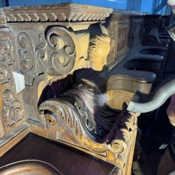 RADIUS LABS SP. Z O.O. | CZYSZCZENIE LASEREM - Szczegółowe czyszczenie rzeźbionej, drewnianej ławy kościelnej z użyciem odkurzacza przemysłowego, widoczne drobinki kurzu unoszące się w powietrzu.