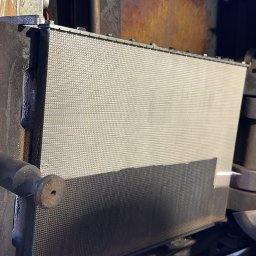 RADIUS LABS SP. Z O.O. | CZYSZCZENIE LASEREM - Metalowa konstrukcja z perforowanym panelem, prawdopodobnie element większej maszyny przemysłowej, z widocznymi śladami użytkowania i rdzawymi nalotami.