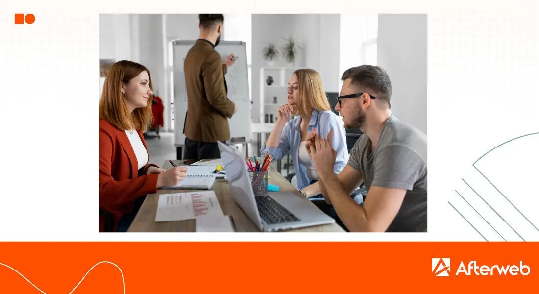 Zespół trzech osób w biurze podczas burzy mózgów: kobieta w czerwonej marynarce notuje, mężczyzna w okularach gestykuluje, a kobieta w niebieskiej koszuli słucha. W tle mężczyzna pisze na białej...