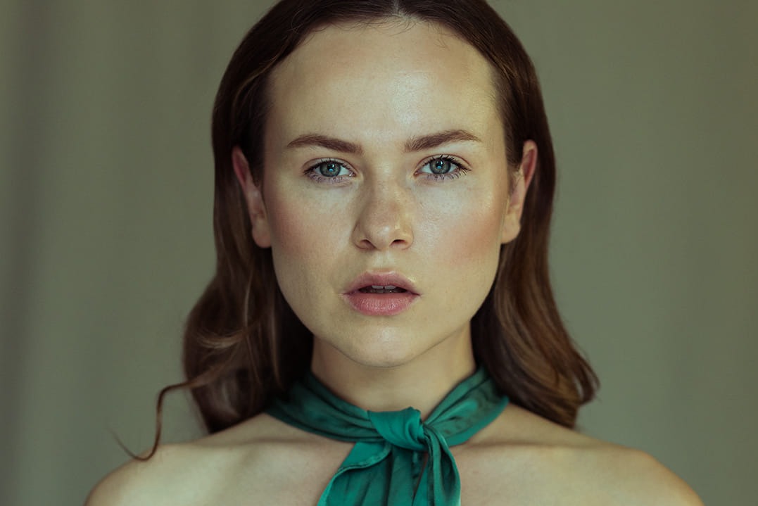 Portret kobiety z zielonym szalem, delikatny makijaż, naturalne światło.