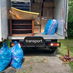 Mario Super clean - Wnętrze busa załadowane kartonami, meblami i workami, widoczne z zewnątrz, z ziemią i trawą w tle.