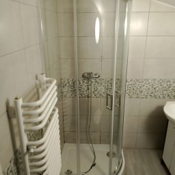 Szymon Michaluk - Kabina prysznicowa z grzejnikiem drabinkowym w łazience w Częstochowie, widoczne płytki ceramiczne na ścianach i podłodze.