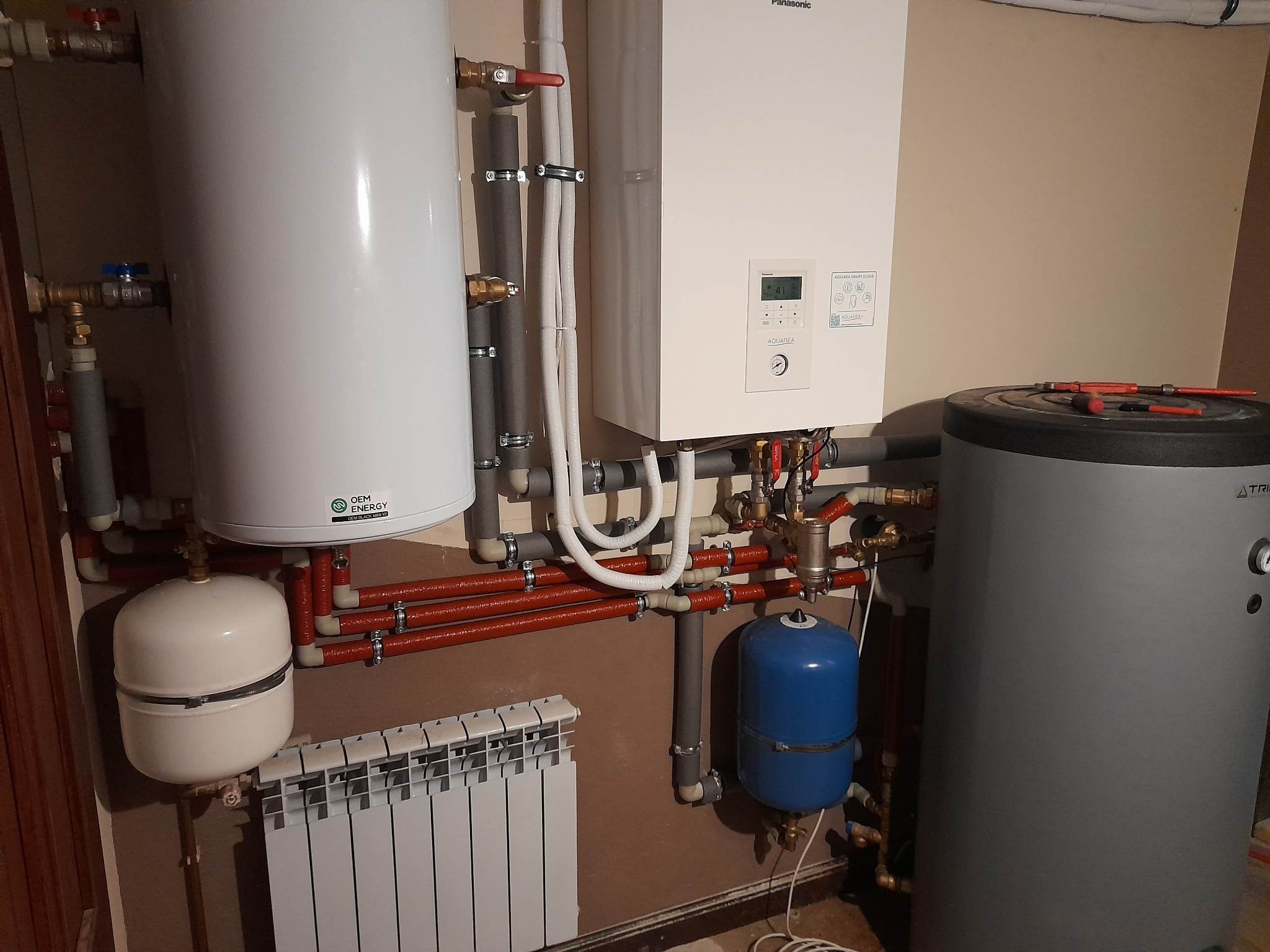 Instalacja grzewcza w kotłowni z piecem gazowym Panasonic Aquarea, grzejnikiem, zbiornikiem buforowym i elementami instalacji hydraulicznymi.