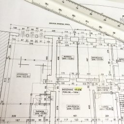 AKRID GROUP Sp,z.oo - Plan mieszkania z naniesionymi wymiarami i układem pomieszczeń, częściowo zakryty przez białą linijkę. Widoczne opisy pomieszczeń i ich powierzchni.