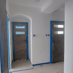 Sąsiad z Wawra - Przygotowane do malowania wnętrze z zabezpieczonymi taśmą malarską drzwiami i listwami, widoczny agregat malarski.