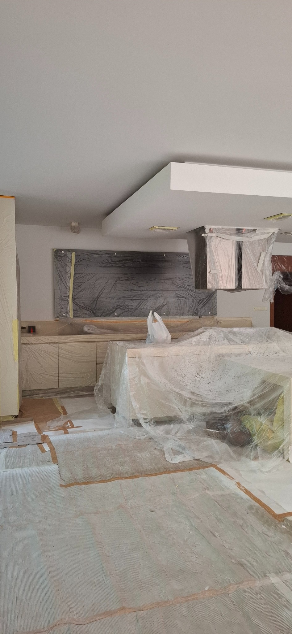 Przygotowanie kuchni do malowania: meble i podłoga zabezpieczone folią malarską i taśmą. Blat przykryty workiem foliowym.