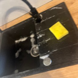 Do Ładu - Czarny zlewozmywak granitowy z armaturą, żółtą gąbką i resztkami piany po umyciu