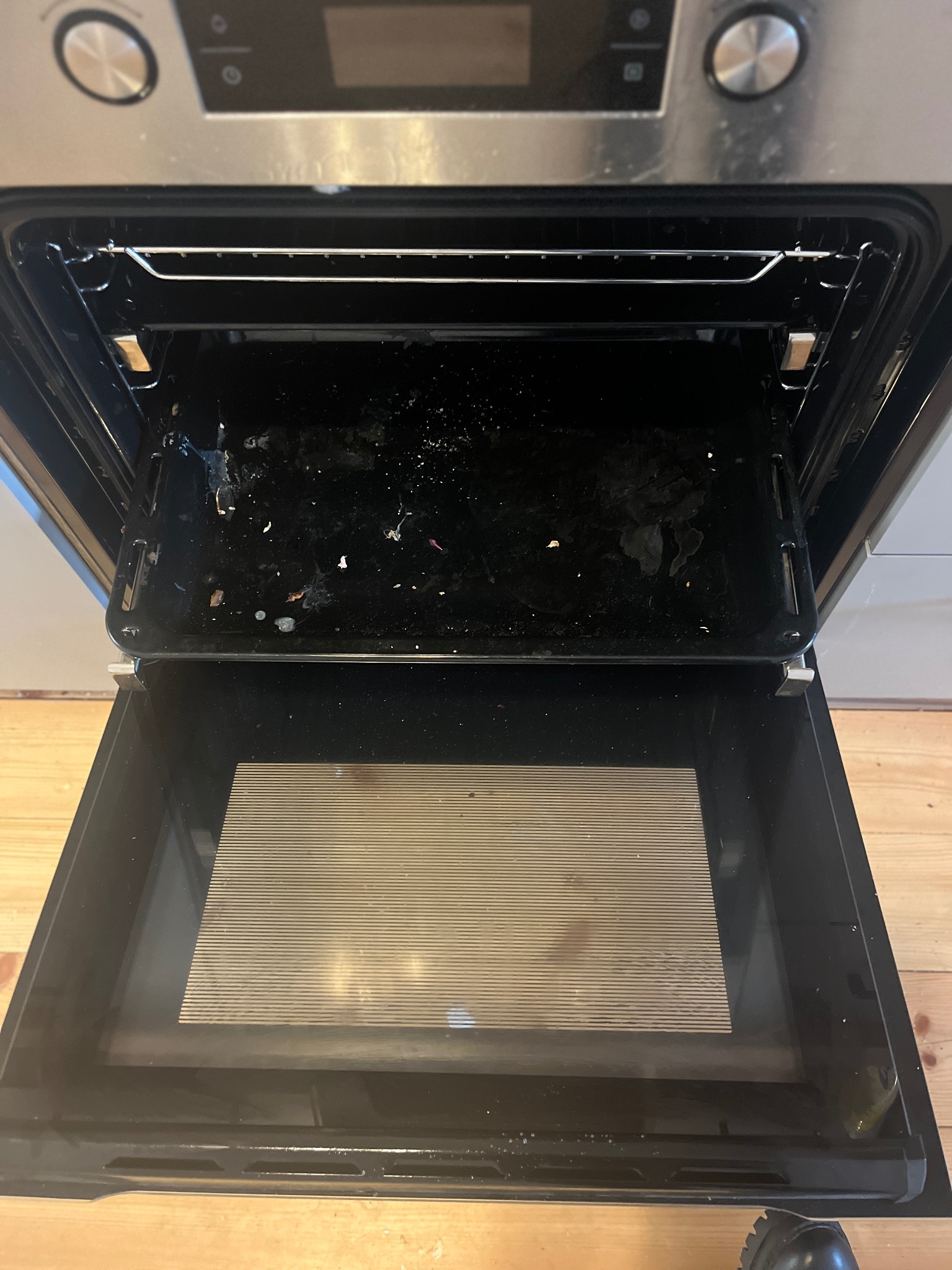 Wnętrze brudnego piekarnika przed czyszczeniem w Siedlcach, widoczne resztki jedzenia na blasze i ściankach.