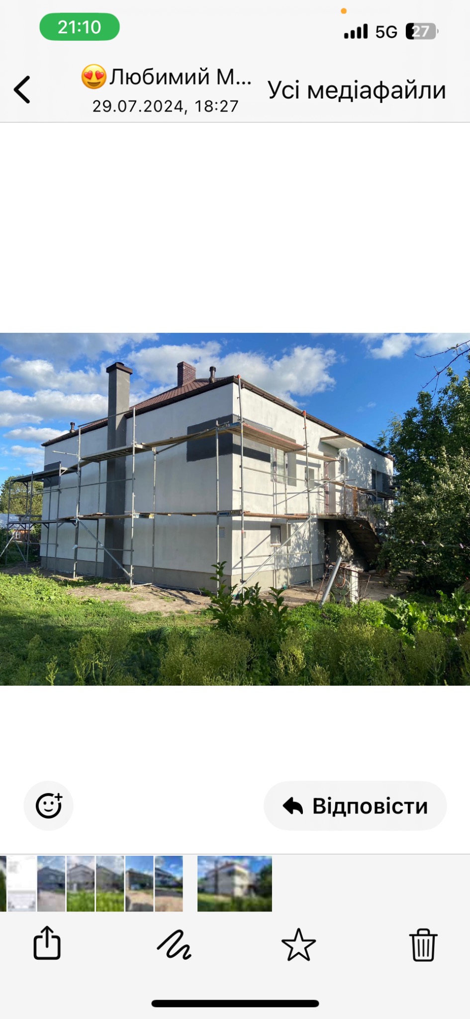 Dwupiętrowy dom w trakcie prac wykończeniowych elewacji, widoczne rusztowania, częściowo pomalowane ściany, nowy komin i brązowy dach, otoczenie zielone.